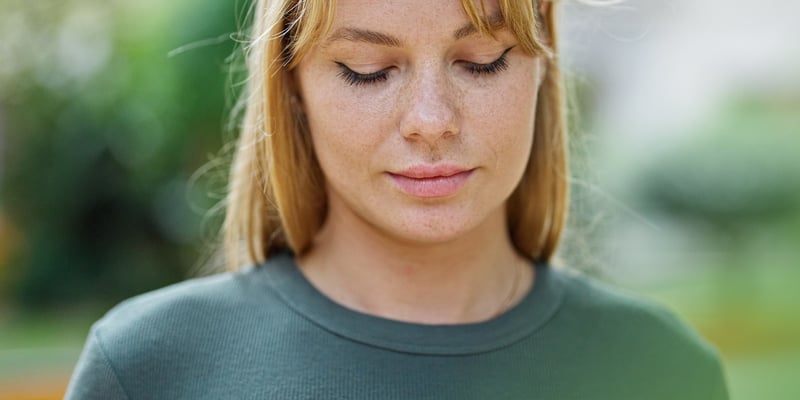 A white girl with green shirt looking down on her phone