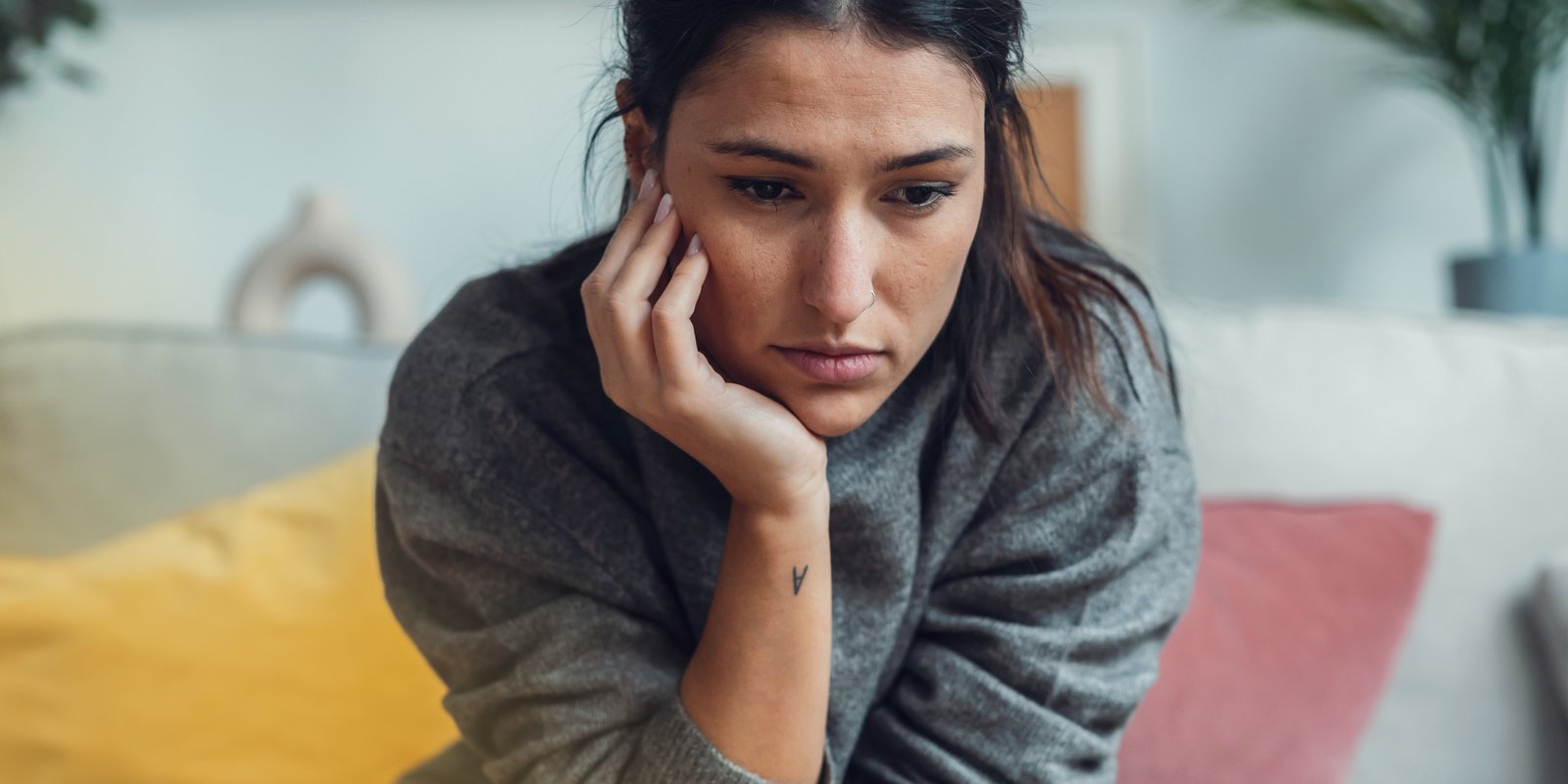 A woman with hand on her chin sitting down and looking worried