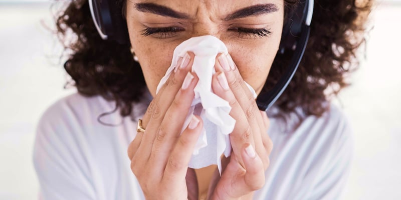 A woman sneezing into a paper towel