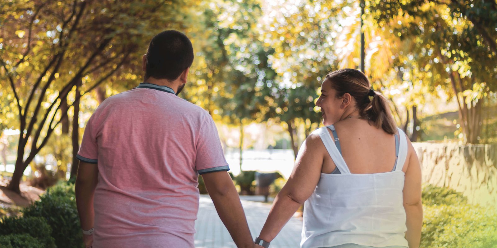 A man and a woman holding hands intimately and walking down the road