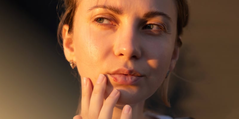 a woman with hands on her chin looking at her sore lips