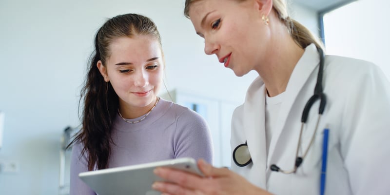 a doctor with an iPad showing a girl the details on the iPad