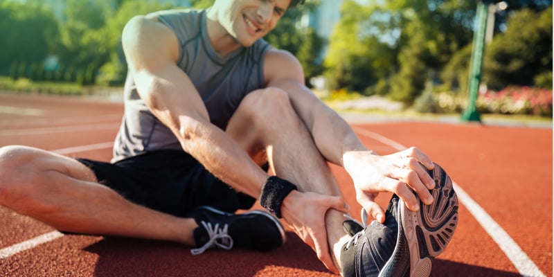 A man holding his leg and gritting his teeth in pain