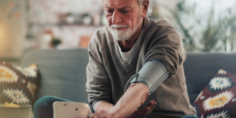 a man sitting down with blood pressure kit checking his blood pressure